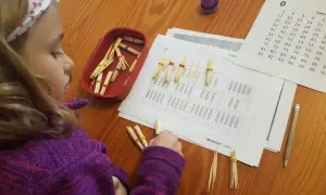 Niña concentrada con pajitas y gomas para resolver operaciones matemáticas, aplicando el método ABN infantil.
