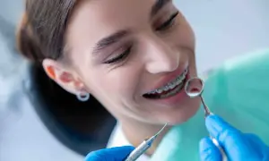 Sorriso con apparecchio ortodontico, mentre il dentista esamina i denti. Nessun mal di denti apparecchio, solo un controllo di routine.
