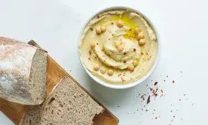 Misternie ułożony hummus z ciecierzycą i oliwą, obok chleba. Czy hummus ma dużo białka? Tak, to świetne źródło!