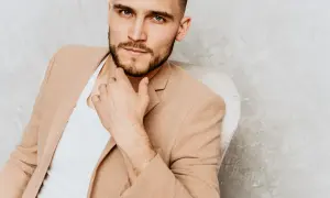 Elegancki mężczyzna w beżowej marynarce, zamyślony, być może zastanawia się, czego pragną mężczyźni.