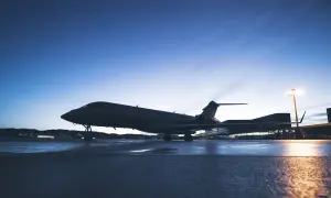 Ein Privatjet steht auf einem nassen Rollfeld bei Dämmerung.