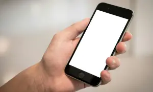 Dłoń trzyma smartfon z pustym ekranem. Chcesz wiedzieć, jak sprawdzić telefon?