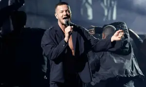 Imagine Dragons koncert Polska: wokalista Dan Reynolds śpiewa na scenie, otoczony tancerzami w mrocznym klimacie.