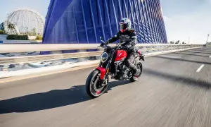 Mujer conduce moto roja por puente moderno. Con 18 años, puedes sacarte el carnet de moto A2.