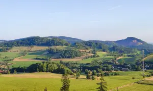 Zielone wzgórza i pola tworzą malowniczy krajobraz, przypominający krainę wygasłych wulkanów. W oddali widać lasy i niewielkie osady.