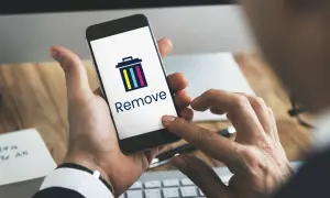Dłoń trzyma smartfon z ikoną kosza i napisem "Remove". Dowiedz się, jak usunąć członka z grupy na Messengerze.