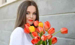 Uśmiechnięta dziewczyna z bukietem pomarańczowych i żółtych tulipanów, idealny prezent na imieniny Anity.