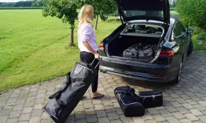Frau packt Gepäck für den Roadtrip. Koffer und Taschen werden in den Kofferraum geladen.