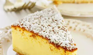 Una fetta di torta alla ricotta veloce e morbidissima, cosparsa di cocco grattugiato, su un piatto bianco.
