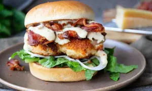 En saftig kycklingburgare med krispigt bacon, sallad, lök och en krämig dressing. Perfekt för ett gott hamburgerdressing recept.