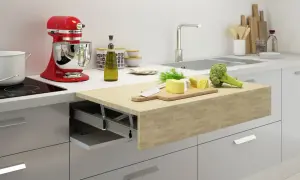 Un piano estraibile sul tavolo della cucina con formaggio, broccoli e un coltello su un tagliere.