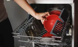 Ręka wkłada czerwony talerz do najlepszej zmywarki 45 cm wolnostojącej.