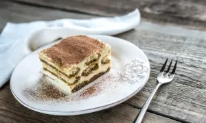 Une part de tiramisu maison, saupoudrée de cacao, sur une assiette blanche, prête à être dégustée. La conservation de ce délice est essentielle.