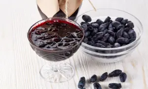 Pyszny dżem z jagody kamczackiej w kielichu, obok miseczka świeżych owoców i słoiczek domowego przetworu.