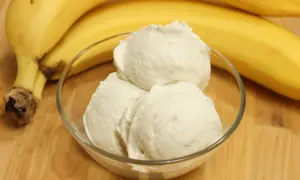Schneebälle aus schnellem Bananeneis in einer Glasschale, daneben reife Bananen.