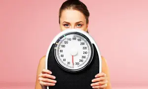 Donna con bilancia, un simbolo per la dieta 1500 calorie e il controllo del peso.