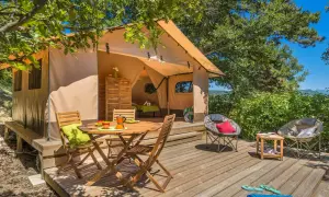 Tente aménagée pour un séjour insolite dans la Drôme, avec terrasse en bois, mobilier de jardin et vue sur la nature.