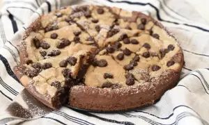 En kladdkaka med cookie dough och chokladbitar, pudrad med florsocker. En bit är uppskuren.