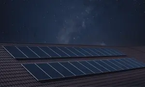 Paneles solares en un tejado bajo un cielo estrellado. La imagen sugiere que los paneles solares funcionan de noche, capturando la energía de las estrellas.