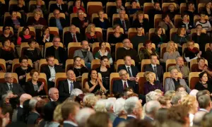 Widownia w teatrze, elegancko ubrani widzowie siedzą w rzędach. Zastanawiasz się, jak się ubrać do teatru? Postaw na klasykę i dobry styl.