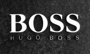 Białe litery "BOSS" na ciemnym, kamiennym tle. Poniżej mniejsze litery "HUGO BOSS". To symbol marki z bogatą historią.