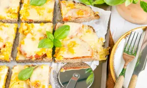 Herzhafte hackfleischpizza vom blech, Landfrauen-Art, mit Tomaten und Käse überbacken, garniert mit frischem Basilikum.