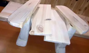 Drewniany taboret DIY, w trakcie budowy, z widocznymi słojami drewna i zaokrąglonymi elementami.