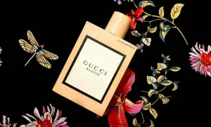 Elegancki flakon Gucci Bloom 100ml na tle kwiecistego wzoru z ważkami.