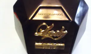 Złote logo "Lady" na ciemnym flakonie perfum, z napisem "Prive" poniżej. Elegancki dodatek dla każdej kobiety.