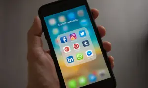 Dłoń trzyma smartfon z ikonami sieci społecznościowych. Szukasz nicków dla chłopaka na Messengera? Tutaj znajdziesz inspiracje!