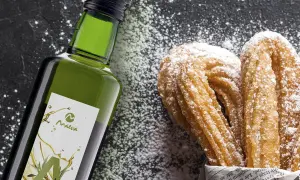 Botella de aceite de oliva junto a churros espolvoreados con azúcar glas.