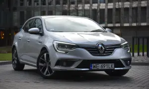 Srebrny Renault Megane 4 z nowoczesnymi żarówkami z przodu, zaparkowany przed budynkiem.