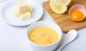 Tazón con salsa holandesa, mantequilla en cubos, limón y yema de huevo. Ingredientes para una deliciosa salsa.