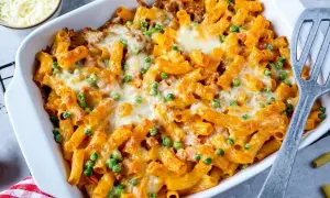 Herzhaftes Rigatoni al Forno mit Erbsen und geschmolzenem Käse in einer Auflaufform, bereit zum Servieren.