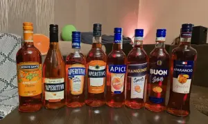 Rząd butelek z pomarańczowym aperitifem, w tym Aperol. Idealne na letnie wieczory.