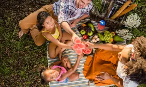 Familia disfrutando un picnic con frutas y bebidas. ¡Excelentes ideas picnic niños para un día soleado!