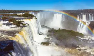 Potężny wodospad Iguazu, z tęczą unoszącą się nad mgłą wodną, otoczony bujną zielenią.