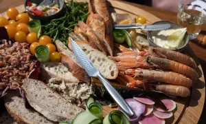 Ein Festmahl mit fisch tapas: Garnelen, Brot, geräucherter Fisch, Tomaten und Gurken auf einem Holzteller.