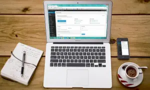 Laptop z panelem WordPress, obok notatnik z planami i telefon. Idealne narzędzia do pracy z XAMPP i WordPress.