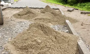 Kopa piasku czeka na ułożenie kostki brukowej. Trudno oszacować, ile piasku na m2 kostki, ale widać, że materiału jest sporo.