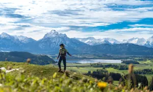 Wanderin genießt Ausblick auf Alpenpanorama, ein perfekter Moment auf den Fernwanderwegen Alpen.