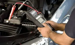 Mechanik sprawdza minimalne napięcie akumulatora do uruchomienia za pomocą testera.
