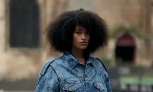 Frau mit Afro-Frisur trägt eine auffällige Jeansjacke, die perfekt zu einem lässigen Baggy Jeans Outfit passt.