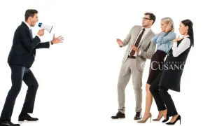 Uomo con megafono urla a tre persone spaventate. Impara a farsi rispettare da un uomo con assertività.