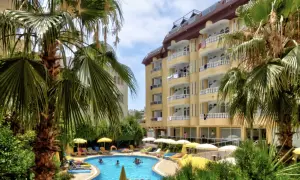 Basen z palmami i żółtym budynkiem hotelowym w tle.