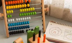 Ábaco de madera con cuentas de colores y un cuaderno con dibujos, ideales para ejercicios de atención y aprendizaje temprano.