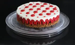 Cheesecake sans cuisson aux framboises, garni de points de coulis rouge sur une base croustillante.