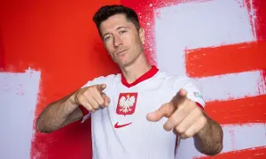 Robert Lewandowski, piłkarz roku uefa, w koszulce reprezentacji Polski, wskazuje palcami w stronę widza.