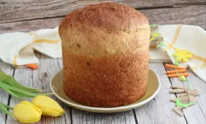 Gâteau de Pâques italien doré, prêt à être décoré d'œufs durs. Tulipes jaunes et décorations de lapin apportent une touche festive.
