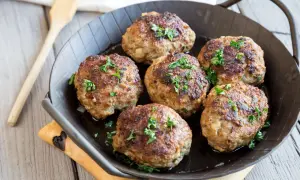 Sechs goldbraune Fleischpflanzerl, garniert mit Petersilie, in einer Pfanne. Ein leckeres Fleischpflanzerl Rezept zum Nachkochen.